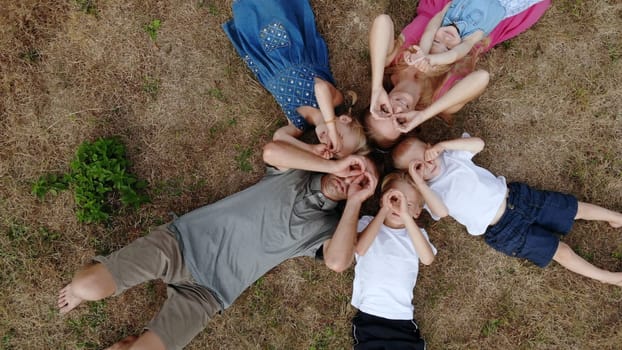 Happy family lies on the grass in the form of sun rays