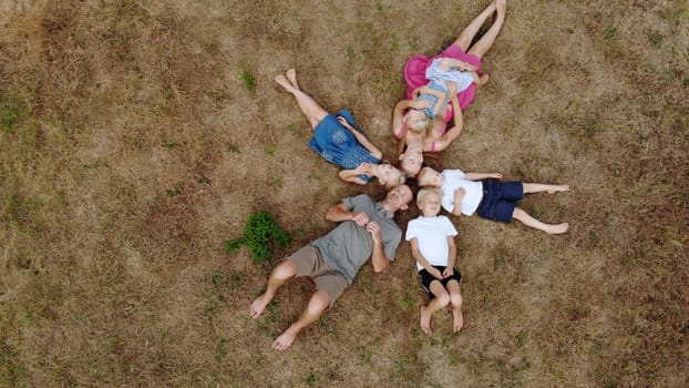 Happy family lies on the grass in the form of sun rays