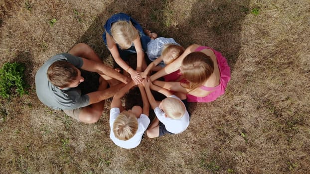 A friendly family joins hands together as a sign of the unity and strength of the family. Drone view