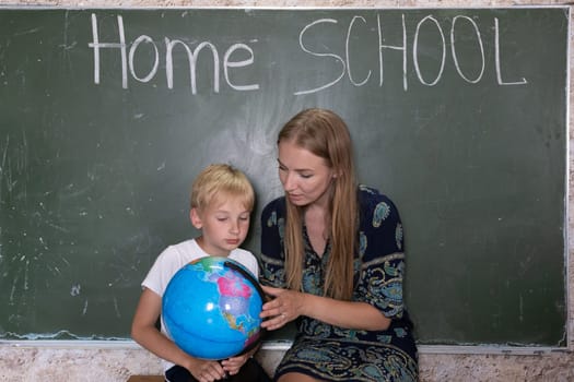 Mother is studying a world map on a globe with her son