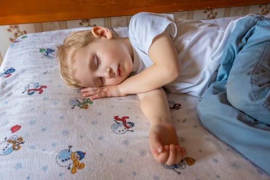 Cute sleeping little boy on the bed at home