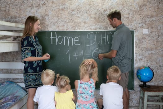 Parents teach their children at the blackboard in their home. Home school