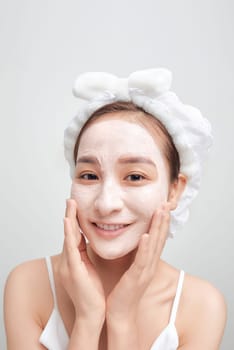 Banner of confident lady in towel on head, touching her face with clay mask