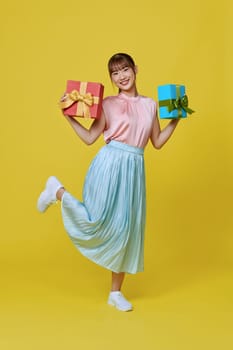 Cheerful attractive woman in red dress with gift on colorful background. Birthday or Valentine's Day.