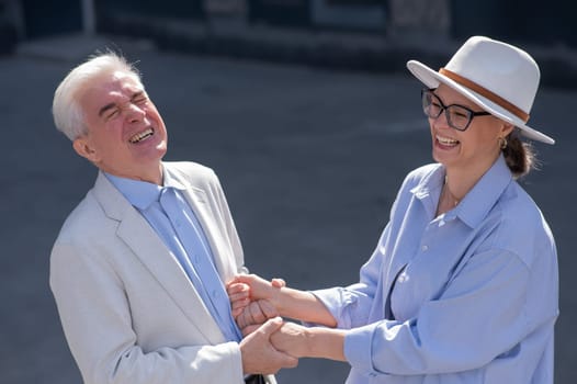 Stylish elderly laughing couple on a walk. Romantic relationships of mature people