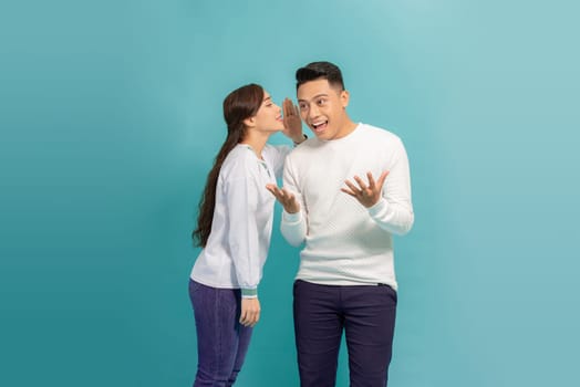 Telling secrets to him. Beautiful young woman holding her mouth near ear of her boyfriend 