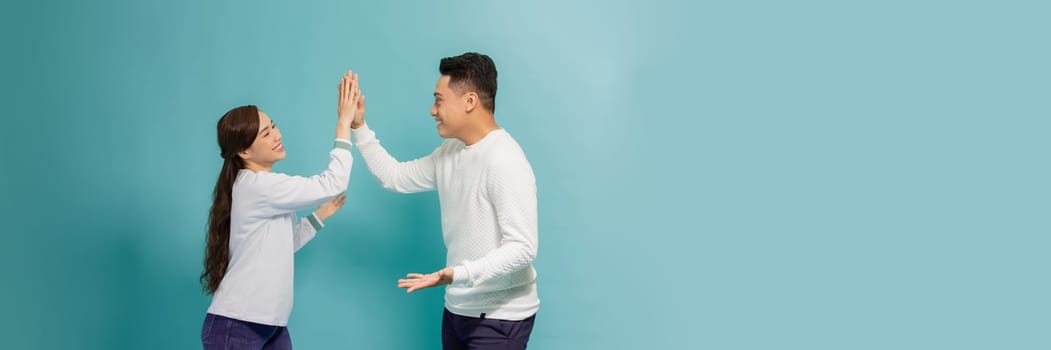 Joyful man and woman greeting each other with a high five isolated on blue banner