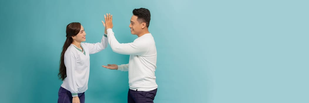 Joyful man and woman greeting each other with a high five isolated on blue banner