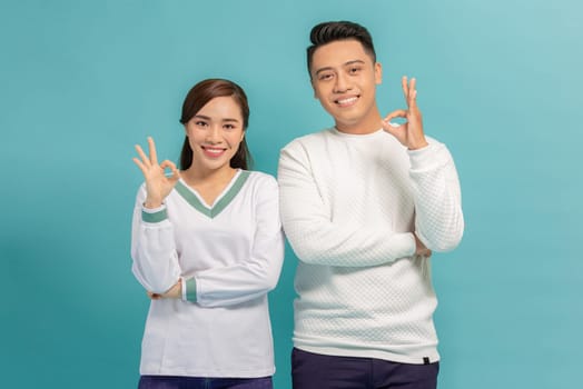 Portrait of young Asian couple showing ok sign isolated on  blue background, Two people concept