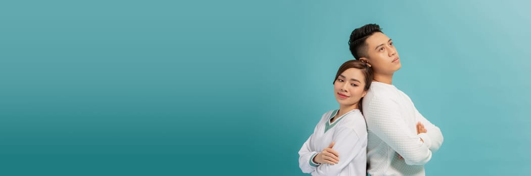 couple man and woman standing back to back with arms crossed isolated over blue banner