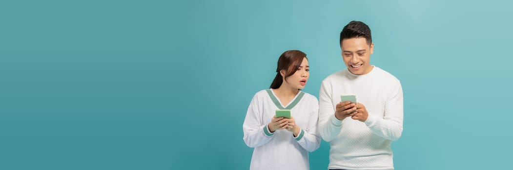 Young asian woman near man, reading message on his phone, trying to peek at screen
