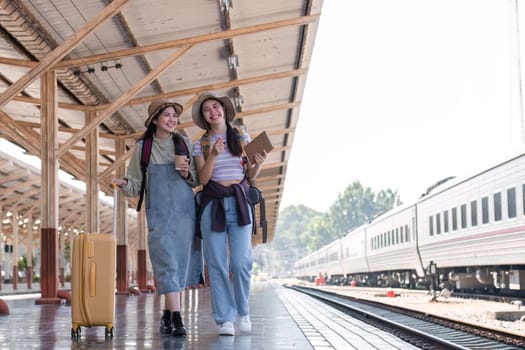 Two Asian female tourist friends are at the train station. Waiting for the train to travel to the provinces together on the weekend..