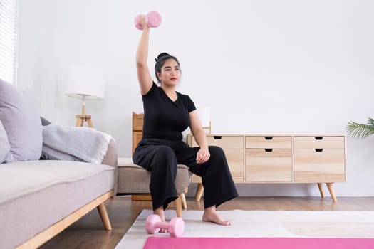 Fat woman exercising at home A beautiful oversized woman in a sports bra and casual pants sits in the living room