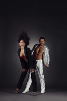 Sexy dancers posing in pair. Studio photo, on grey background