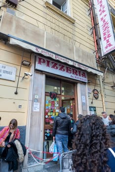 Napoli, Italy: 2023 November 18: People waiting on the street at La Antica Pizzeria Da Michele from 1870 where the authentic Margherita pizza is made in November 2023.