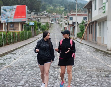 two women in sporty clothes doing rural tourism in a small and lonely village next to a mountain. backpacker day. High quality photo