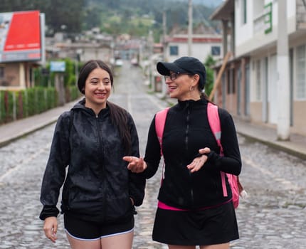 mother and daughter doing rural tourism in sportswear walking on a stone path in the city with two backpacks. backpackers' day. High quality photo