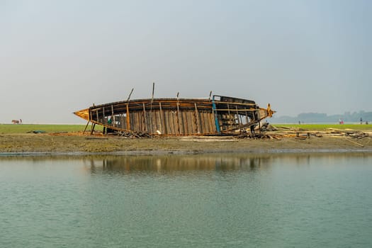 Repairing a wooden boat on the riverbank in Bangladesh