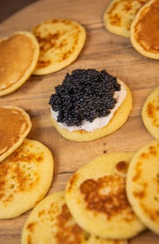 Blinis with black caviar and cream cheese, on a festive dish, mini pancakes, an elegant appetizer, High quality photo