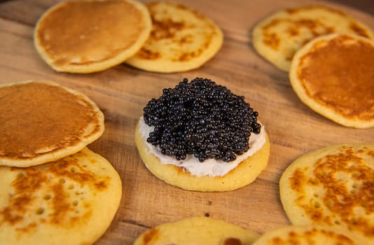 Blinis with black caviar and cream cheese, on a festive dish, mini pancakes, an elegant appetizer, High quality photo