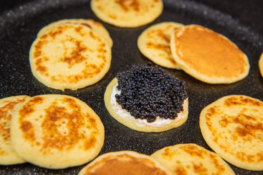 Blinis with black caviar and cream cheese, on a festive dish, mini pancakes, an elegant appetizer, High quality photo