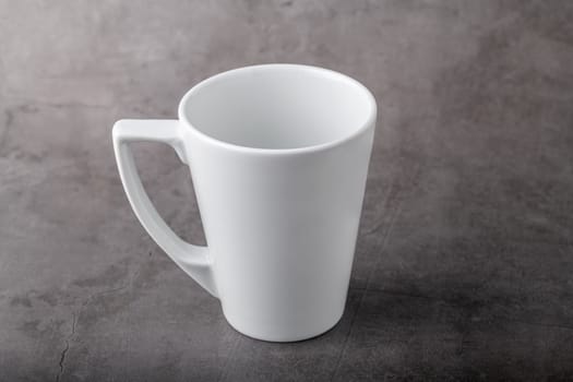 Empty white porcelain cup on gray stone background