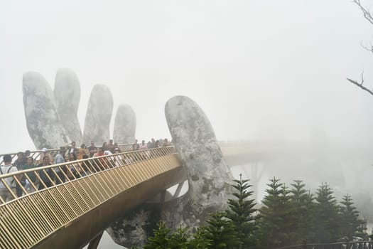 Danang, Vietnam - June 27, 2023: The Golden Bridge is lifted by two giant hands in the tourist resort on Ba Na Hill in Danang, Vietnam.