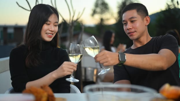 Shot of young Asian couple toasting champagne and enjoying lunch together at a rooftop restaurant