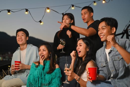 Group of millennial people friends chilling and enjoying hangout time together at rooftop party