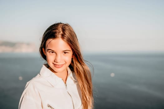 Brown-haired young romantic teenager girl corrects long hair on beach at summer evening wind