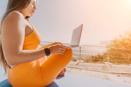 Digital nomad, Business woman working on laptop by the sea. Pretty lady typing on computer by the sea at sunset, makes a business transaction online from a distance. Freelance, remote work on vacation