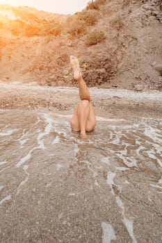 Woman travel sea. Young Happy woman in a long red dress posing on a beach near the sea on background of volcanic rocks, like in Iceland, sharing travel adventure journey