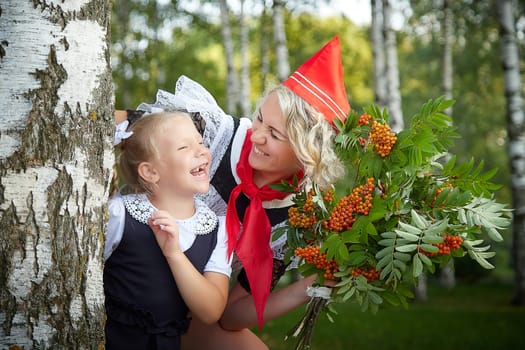 Young and adult schoolgirl on September 1, mother and daughter having fun and joy. Generations of schoolchildren of USSR and Russia. Female pioneer in red tie and October girl in modern uniform