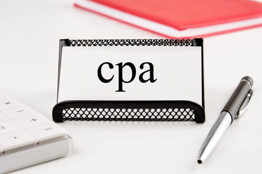 CPA, Certified Public Accountant or Cost per Action the word on the business card standing on a stand next to a notepad, calculator and pen