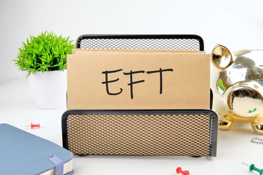 EFT text on paper next to piggy bank, notepad, flower on a white background
