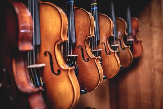 Row of multiple violins hanging on the wall