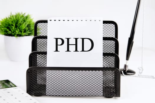 PHD A word written on a piece of paper from a notebook on a stand on a white background
