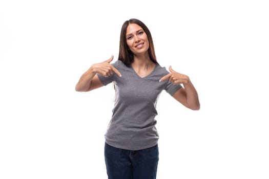 young kind smiling slender brunette promoter woman dressed in a gray t-shirt with space for print on a white background.