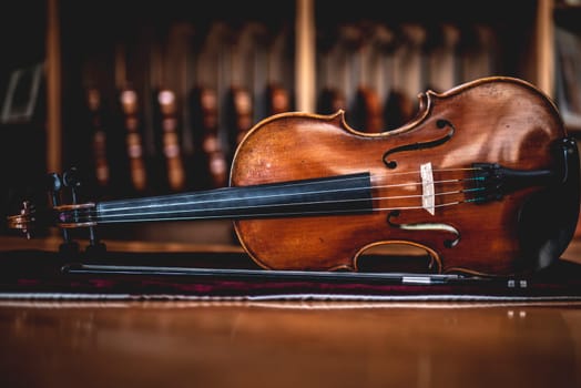 handmade viola leaning sideways with a row of violins on the background