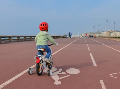 Girl in helmet learns riding a four-wheeled bicycle