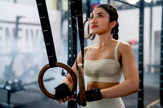 Portrait of pretty Asian woman stand with hold loop for exercise and look up after relax of training in fitness gym.