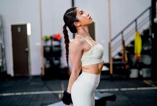 Asian woman with sportwear stand with stretching action in fitness gym and relax after exercise.