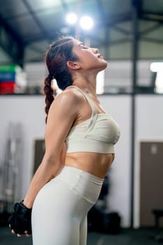 Asian woman with sportwear stand with stretching action in fitness gym and relax after exercise.