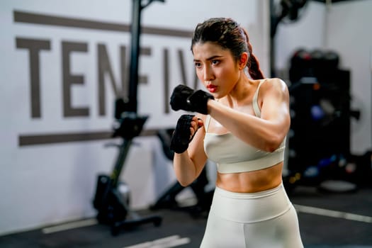 Asian woman action of boxing and training alone in fitness gym and she look concentrate to practice for competition.