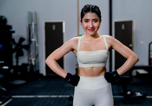 Asian sport woman stand feet waist and look at camera after exercise in fitness gym with happiness.