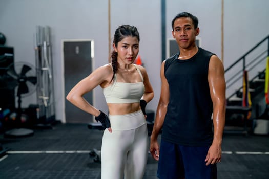 Asian sport man and woman stand together and look at camera with confidence action in fitness gym.