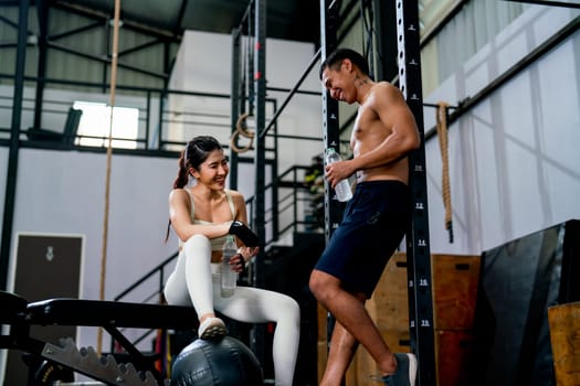 Asian woman and man sit and stand in fitness gym with relax activity also look happiness after training and practice in fitness gym.