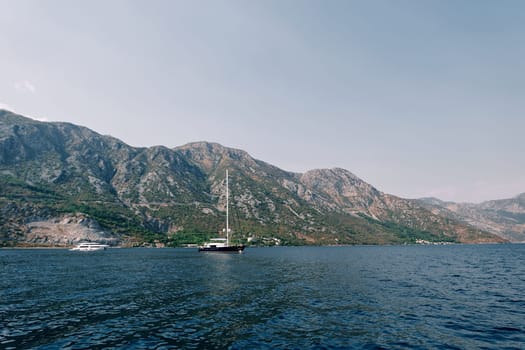 Sailboat sails on the blue sea along a mountain ridge. High quality photo