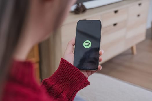 CHIANG MAI, THAILAND - JAN 3 ,2024: Woman holding a iPhone Xs opening spotify app, Spotify is a music service that offers legal streaming music..