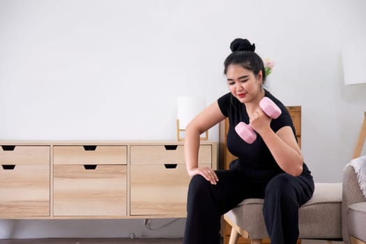 Fat woman exercising at home A beautiful oversized woman in a sports bra and casual pants sits in the living room and exercises